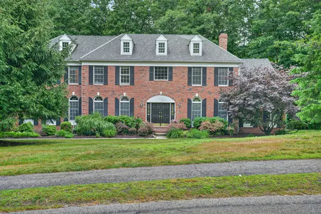 Front exterior of a brick Colonial home with landscaped lawn in Hopkinton, MA